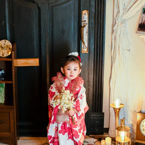 花束を持って立つ、フリル衿の着物の3歳の女の子
