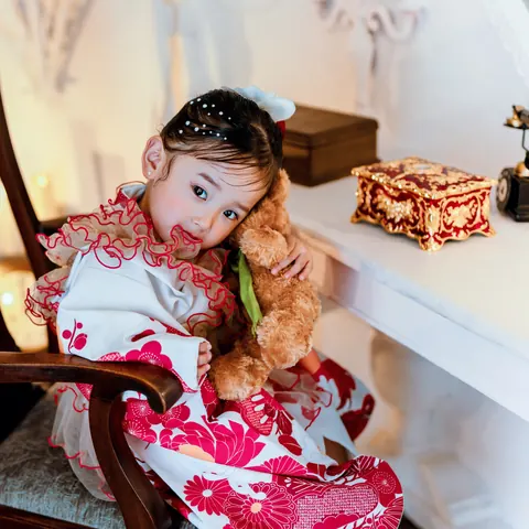 くまのぬいぐるみを抱く、フリル衿の着物の3歳の女の子
