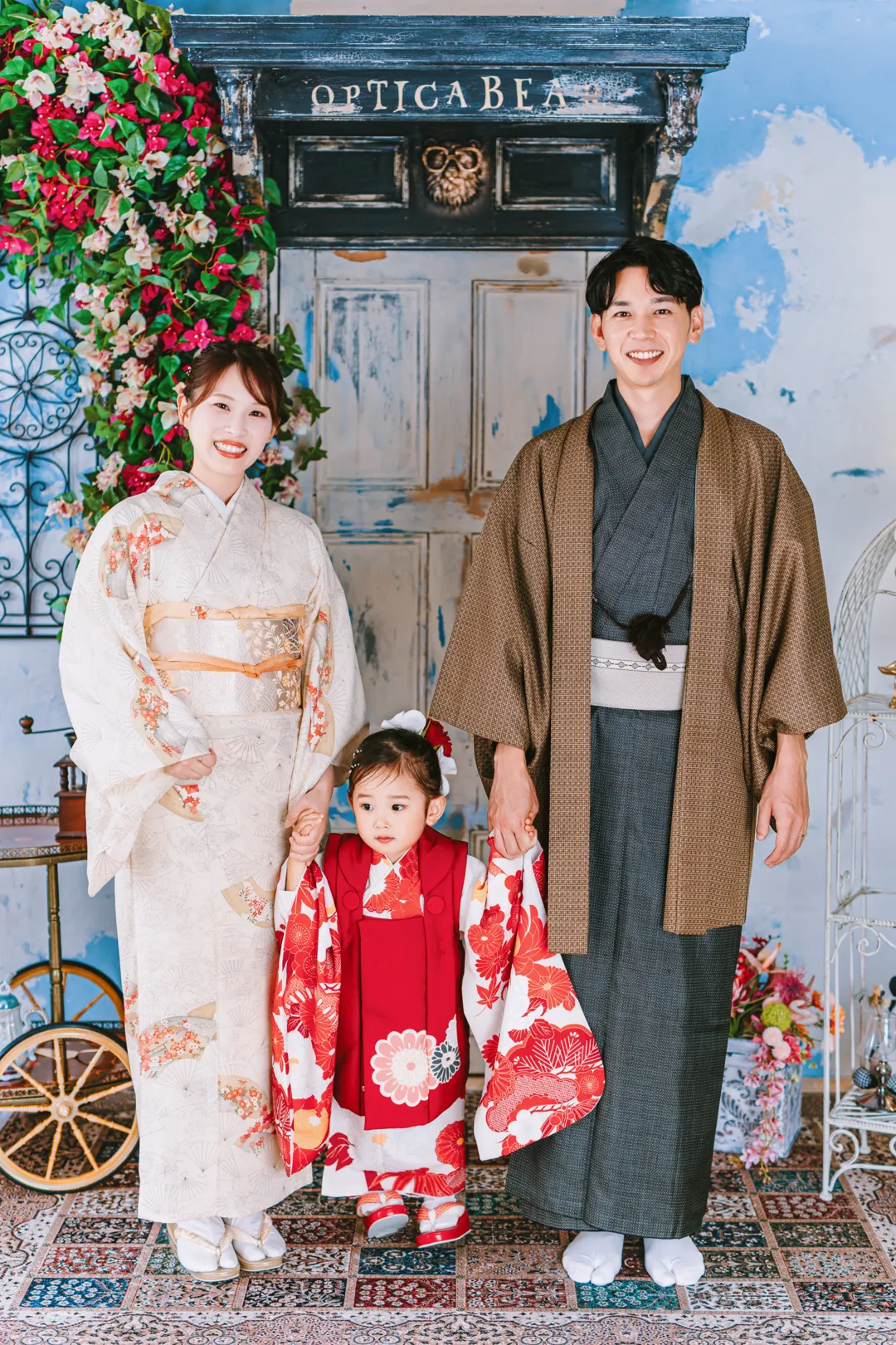 眼鏡屋の前に並ぶ、着物のお父さん・お母さんと赤い被布の女の子